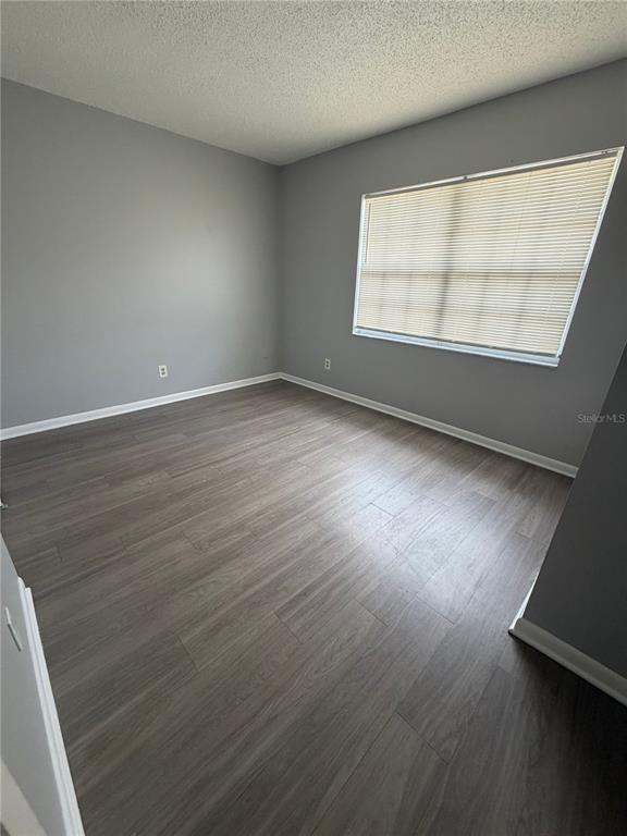 An empty bedroom features gray walls, wood-look flooring, and a window with horizontal blinds — 709 OCEANSIDE CIRCLE UNIT 712, RUSKIN, FL