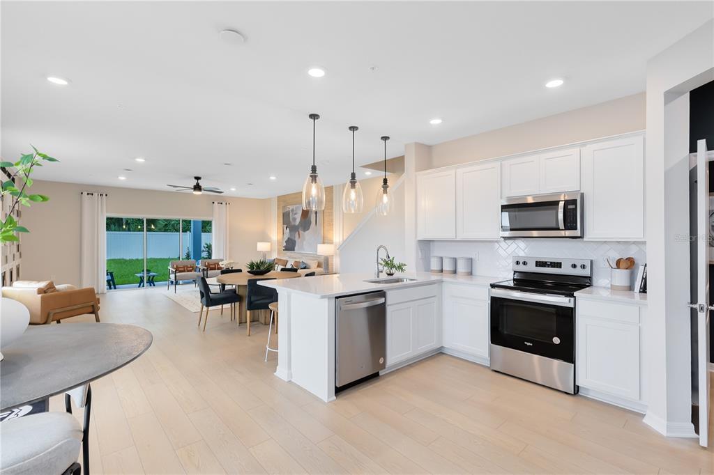 A modern open-concept kitchen features white cabinetry, stainless steel appliances, and a central island — 5114 MORNING DEW LANE, WEST MELBOURNE, FL