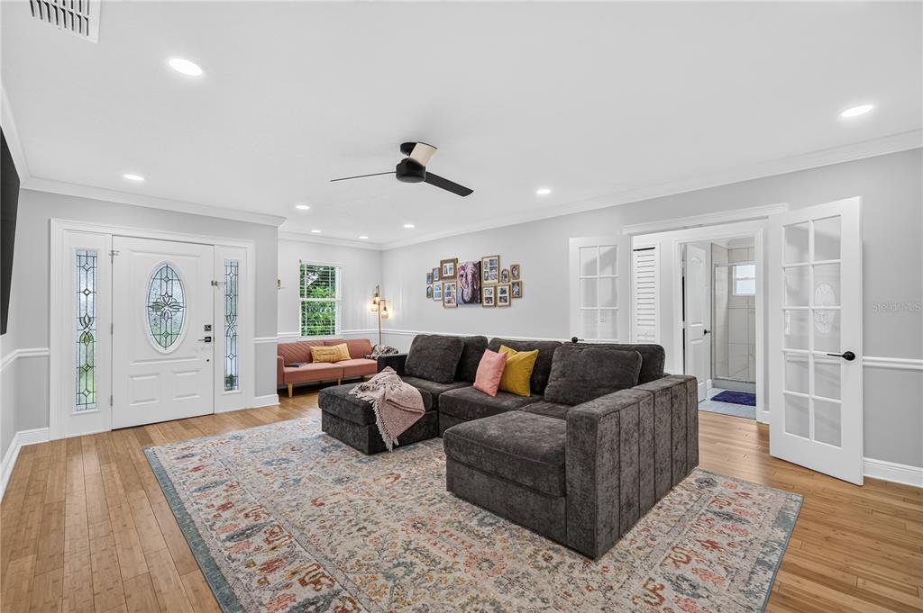 A bedroom with light wood floors, a rattan headboard, a large area rug, and wall decor — 2028 ILLINOIS STREET, ORLANDO, FL