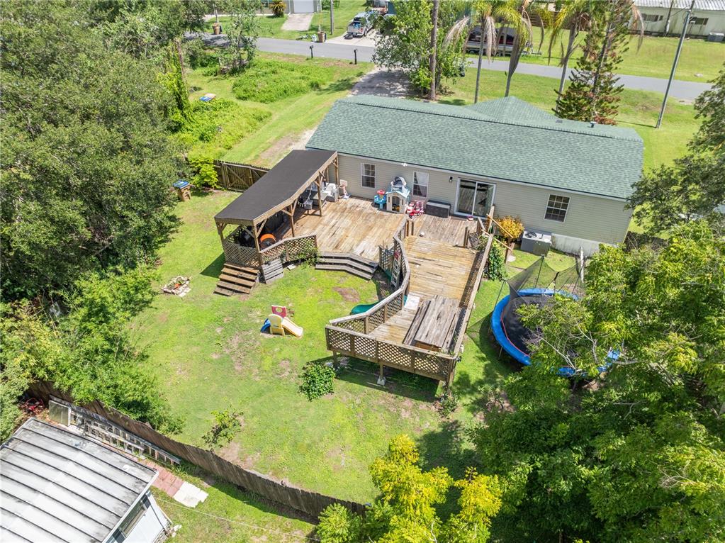An aerial view shows a house with a large wooden deck and a backyard trampoline — 6411 WOODS STREET, ST CLOUD, FL