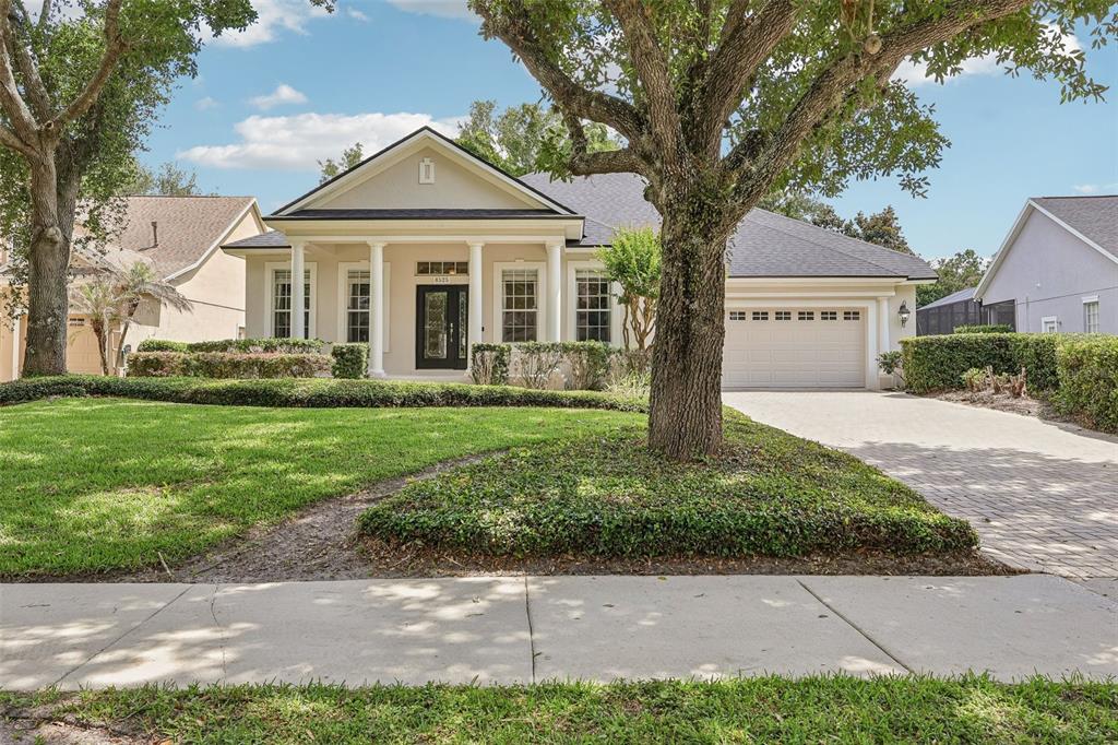 A single-story house with a columned front porch, a paved driveway, and mature trees — 8525 BOWDEN WAY, WINDERMERE, FL