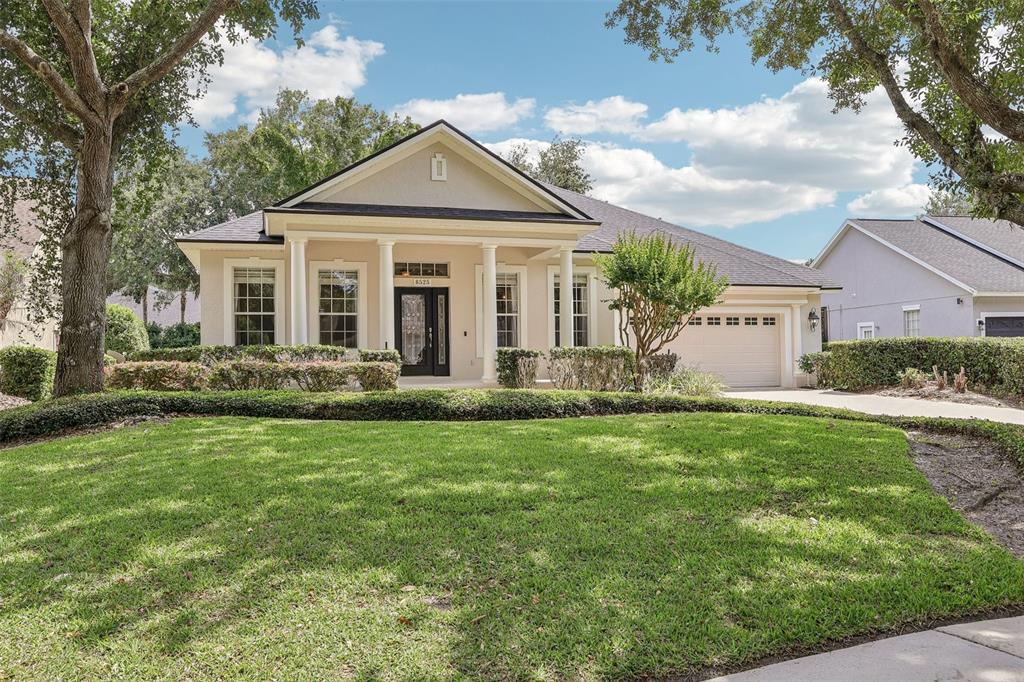 A single-story house with a beige stucco exterior, white columns, and a two-car garage — 8525 BOWDEN WAY, WINDERMERE, FL