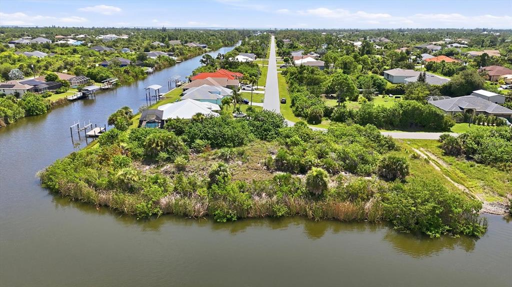 An aerial view shows a waterfront residential lot with a canal and surrounding suburban homes — 15296 ALDAMA CIRCLE, PORT CHARLOTTE, FL