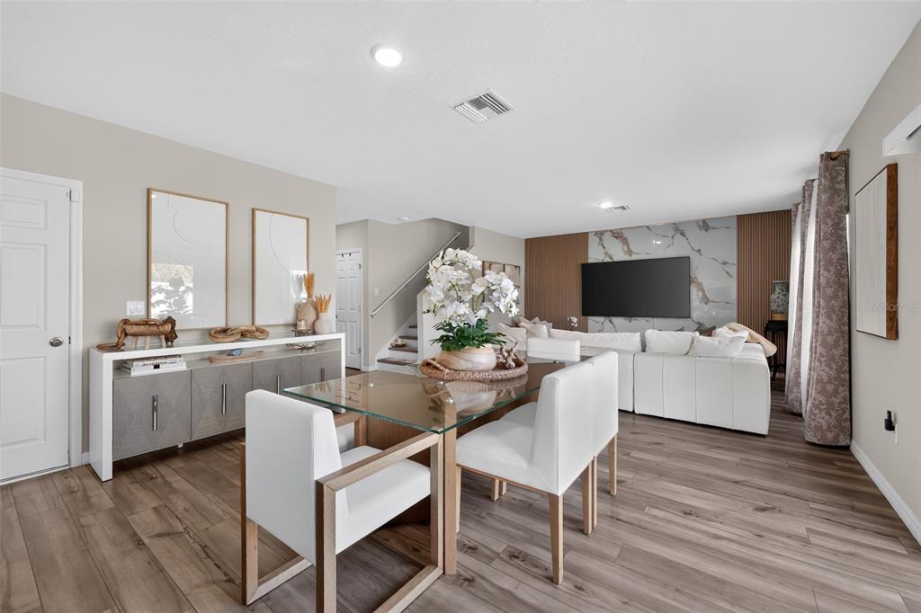 A dining area with a glass table and white chairs sits before a living room — 1857 GRASMERE STREET, HAINES CITY, FL