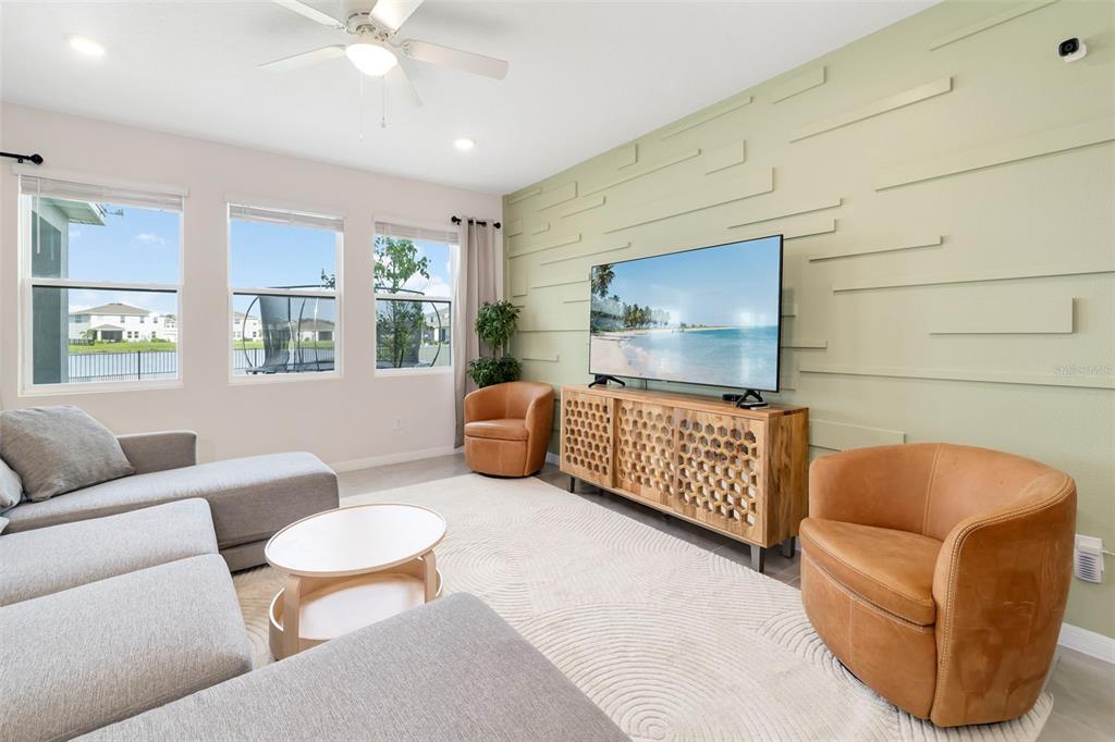 A living room features a light green accent wall, grey sectional sofa, and two leather chairs — 523 158TH STREET E, BRADENTON, FL