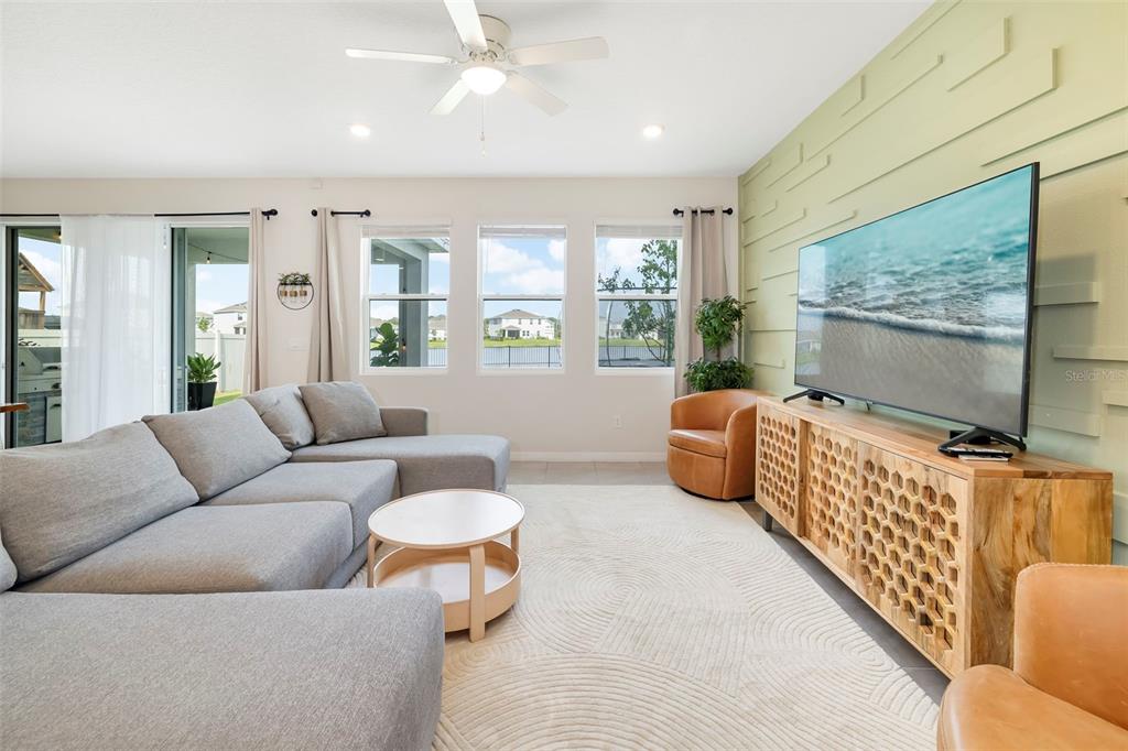 A living room features a grey sectional sofa, a wooden media console, and a green accent wall — 523 158TH STREET E, BRADENTON, FL