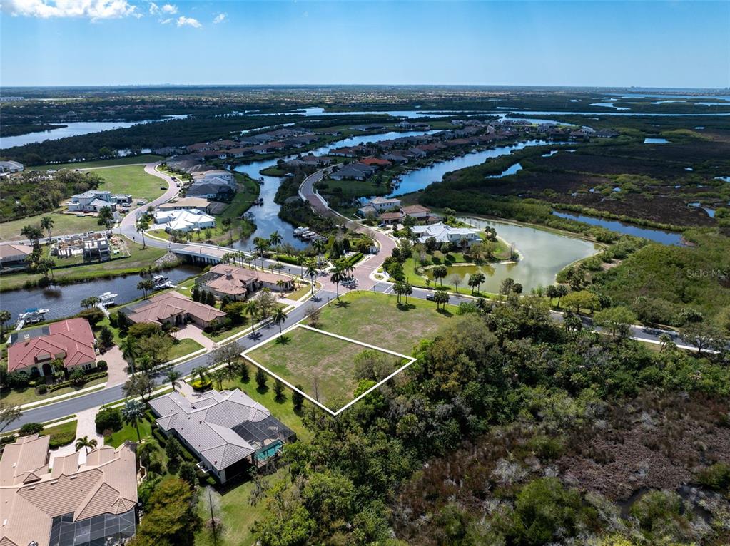 An aerial view shows a vacant residential lot outlined in white within a coastal community — 11708 RIVER SHORES TRAIL, PARRISH, FL