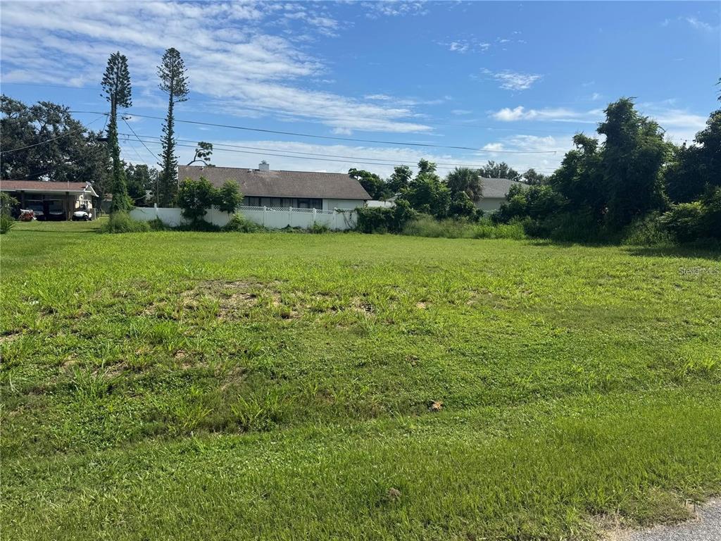 A vacant, grassy residential lot with trees and neighboring houses in the background — ROSLYN ROAD, VENICE, FL