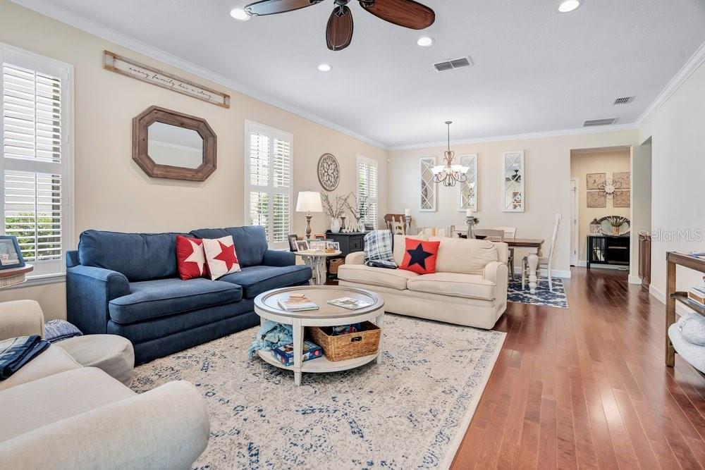 A living room features a blue sofa, a cream sofa, a coffee table, and hardwood floors — 1205 GREENE SQUARE, CELEBRATION, FL