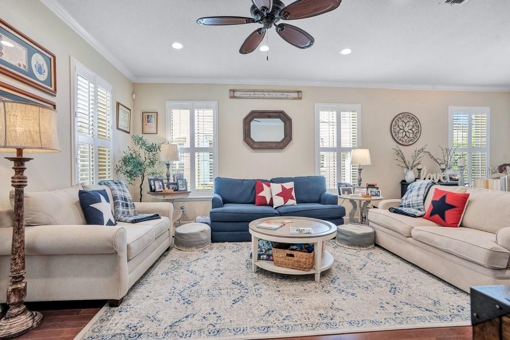 A living room features a blue sofa, two beige sofas, a coffee table, and area rug — 1205 GREENE SQUARE, CELEBRATION, FL