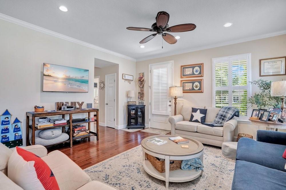 A living room with hardwood floors, a ceiling fan, a sofa, and a television — 1205 GREENE SQUARE, CELEBRATION, FL