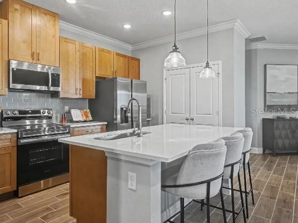 A kitchen features light wood cabinets, stainless steel appliances, a white island, and tile flooring — 17683 NW 169TH PLACE, ALACHUA, FL