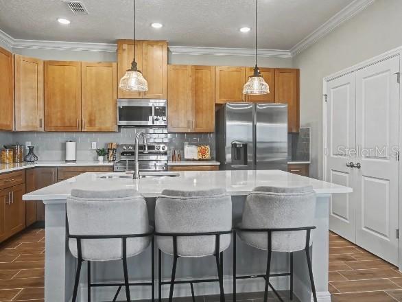 A kitchen with light wood cabinets, a white island, and three grey bar stools — 17683 NW 169TH PLACE, ALACHUA, FL