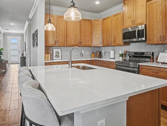 A kitchen features a white quartz island, wooden cabinets, stainless steel appliances, and gray tile — 17683 NW 169TH PLACE, ALACHUA, FL