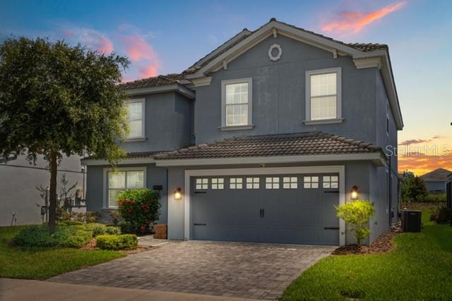 A two-story blue house with a two-car garage and a paved driveway at sunset — 8909 STINGER DRIVE, CHAMPIONS GATE, FL