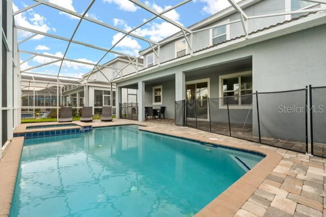 A swimming pool with a spa sits inside a screened lanai next to a house — 8909 STINGER DRIVE, CHAMPIONS GATE, FL