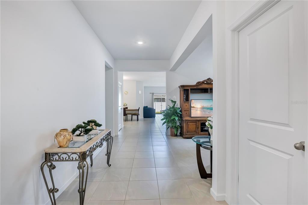 A tiled hallway leads from a white door toward an open living area and dining room — 437 SILVER PALM DRIVE, HAINES CITY, FL