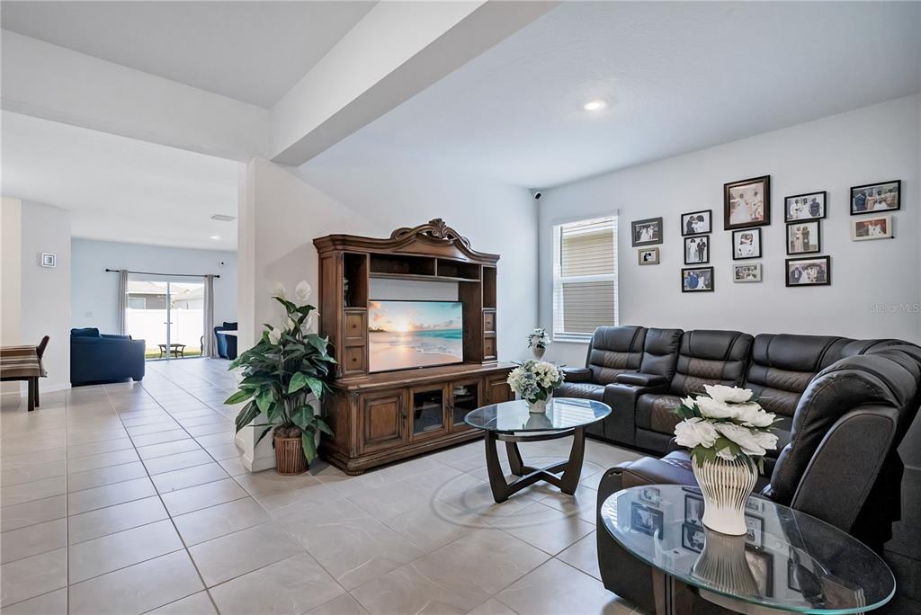 A living room features a wooden entertainment center, leather sectional, and tile flooring — 437 SILVER PALM DRIVE, HAINES CITY, FL