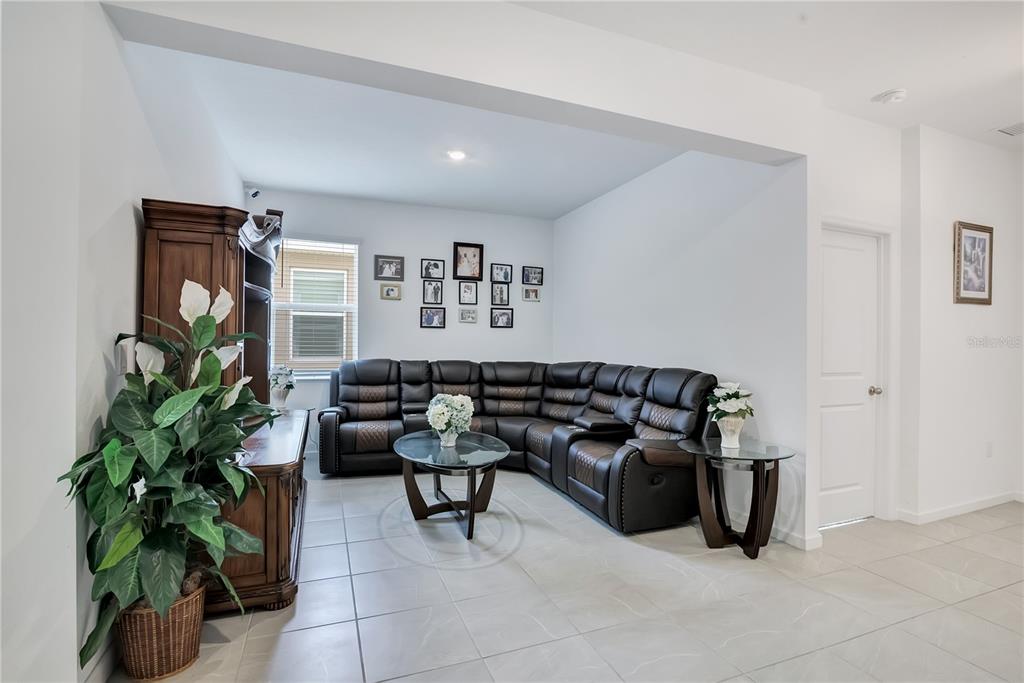 A living room features a large brown sectional sofa, a glass coffee table, and tile flooring — 437 SILVER PALM DRIVE, HAINES CITY, FL