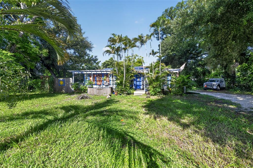 A single-story house with a blue door and porch surrounded by palm trees and greenery — 806 35TH STREET W, BRADENTON, FL