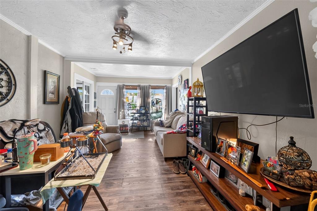 A living room features wood-look flooring, a large wall-mounted television, and a ceiling fan — 806 35TH STREET W, BRADENTON, FL