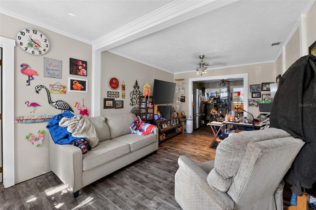 A living room features a beige sofa, a recliner, wood-look flooring, and flamingo-themed wall decor — 806 35TH STREET W, BRADENTON, FL