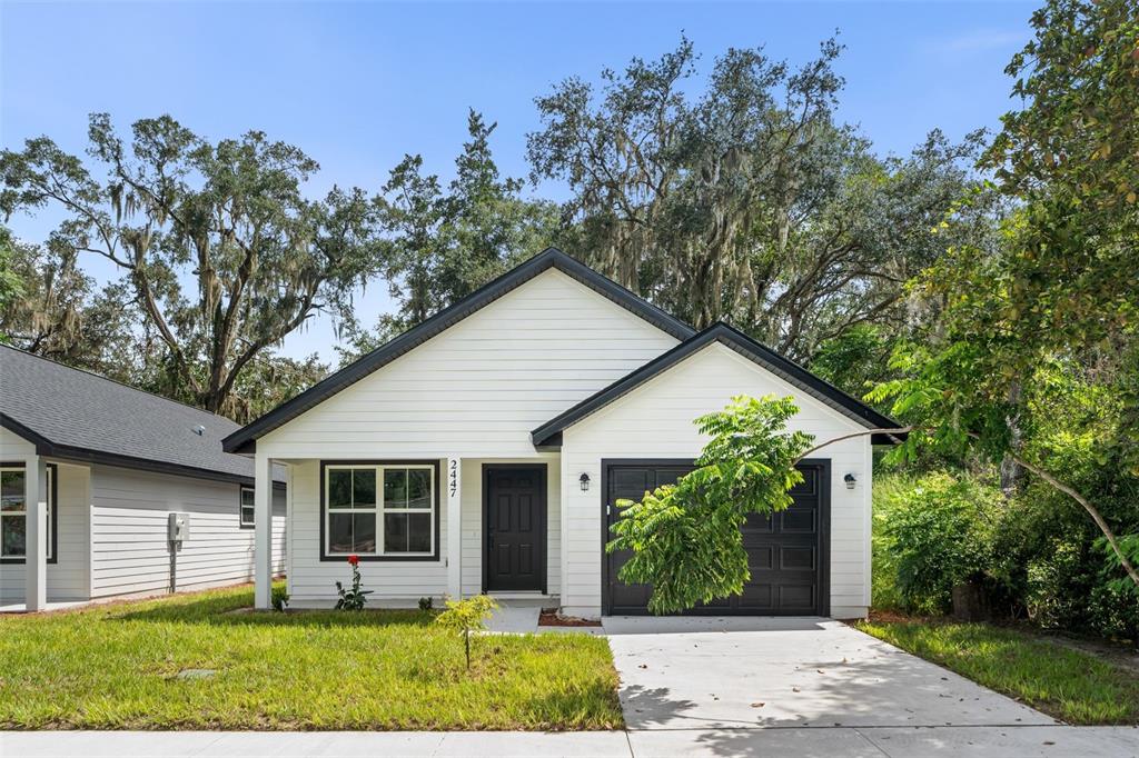 An open-concept kitchen and living area with white cabinets, granite countertops, and wood-look flooring — 2447 SE 10TH AVENUE, GAINESVILLE, FL