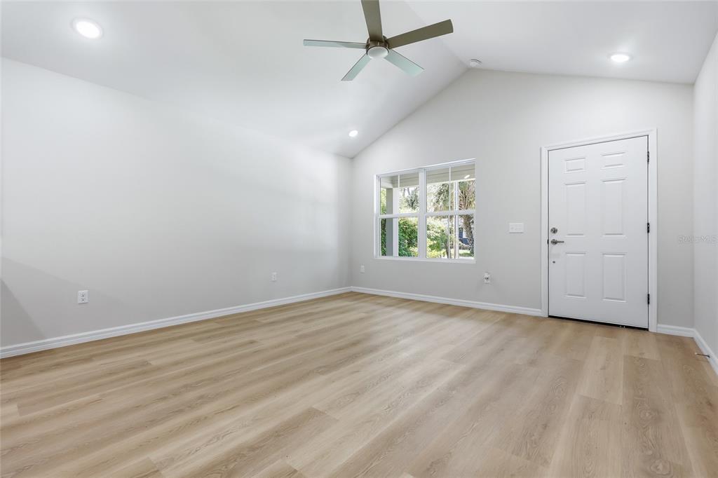 A kitchen features white cabinets, granite countertops, a central island, and light wood-look flooring — 2447 SE 10TH AVENUE, GAINESVILLE, FL