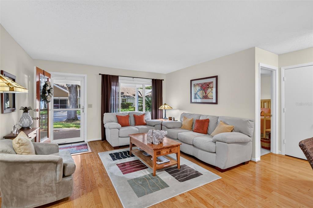 A living room features light-colored sofas, a wooden coffee table, and hardwood floors — 8591 SW 93RD PLACE UNIT C, OCALA, FL