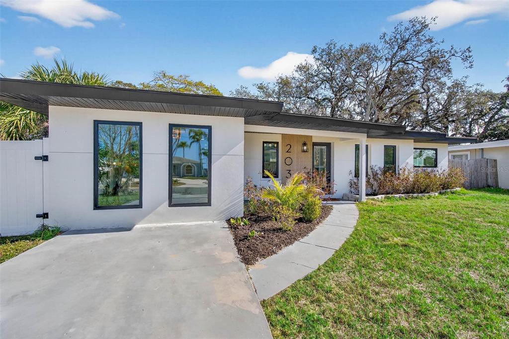 An open-concept kitchen and living area featuring a blue marble island and slatted wood wall — 203 DRIFTWOOD DRIVE W, PALM HARBOR, FL