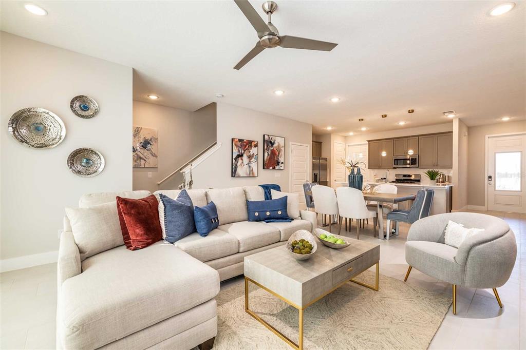 A living room with a sectional sofa, coffee table, and an open kitchen in the background — 7921 SPECTRUM DRIVE, KISSIMMEE, FL