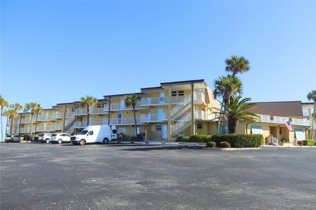 A three-story apartment building with exterior staircases and palm trees in a parking lot — 7900 A1A S UNIT A214, ST AUGUSTINE, FL