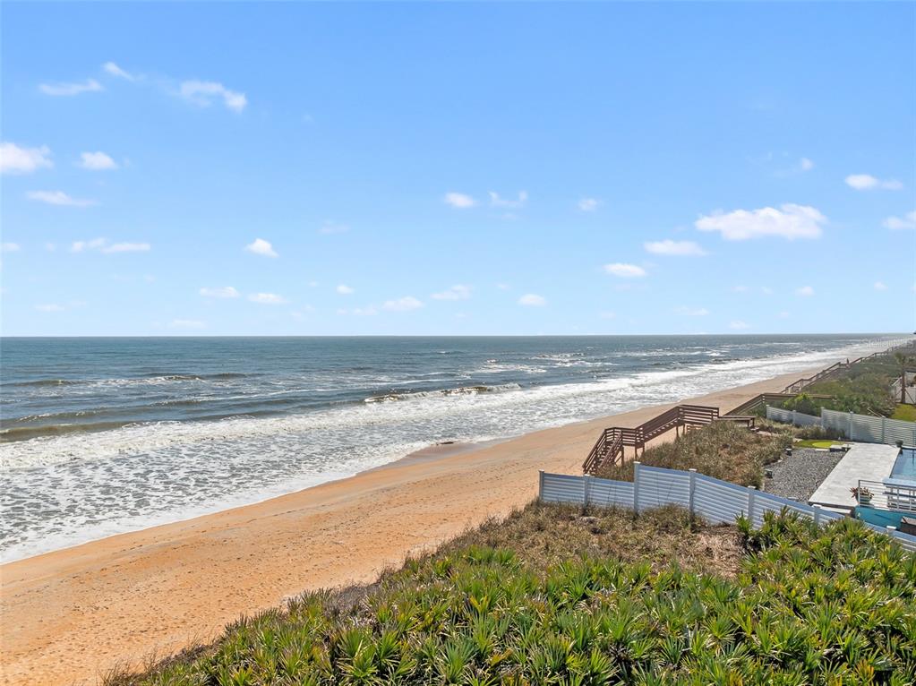 An elevated view of a sandy beach with a wooden staircase and white fencing — 3101 N OCEAN SHORE BOULEVARD, FLAGLER BEACH, FL