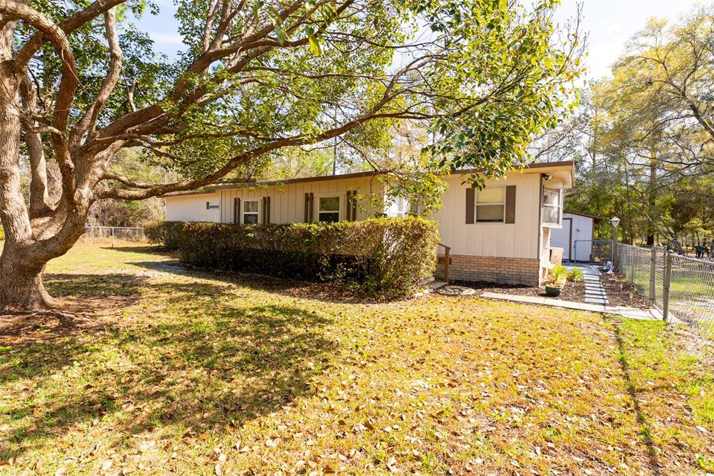 A mobile home with a screened-in porch and a paved walkway in a grassy yard — 14881 NE 147TH AVENUE, FORT MC COY, FL