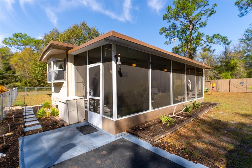 A single-story house with light-colored siding and a brick base sits on a grassy lot — 14881 NE 147TH AVENUE, FORT MC COY, FL