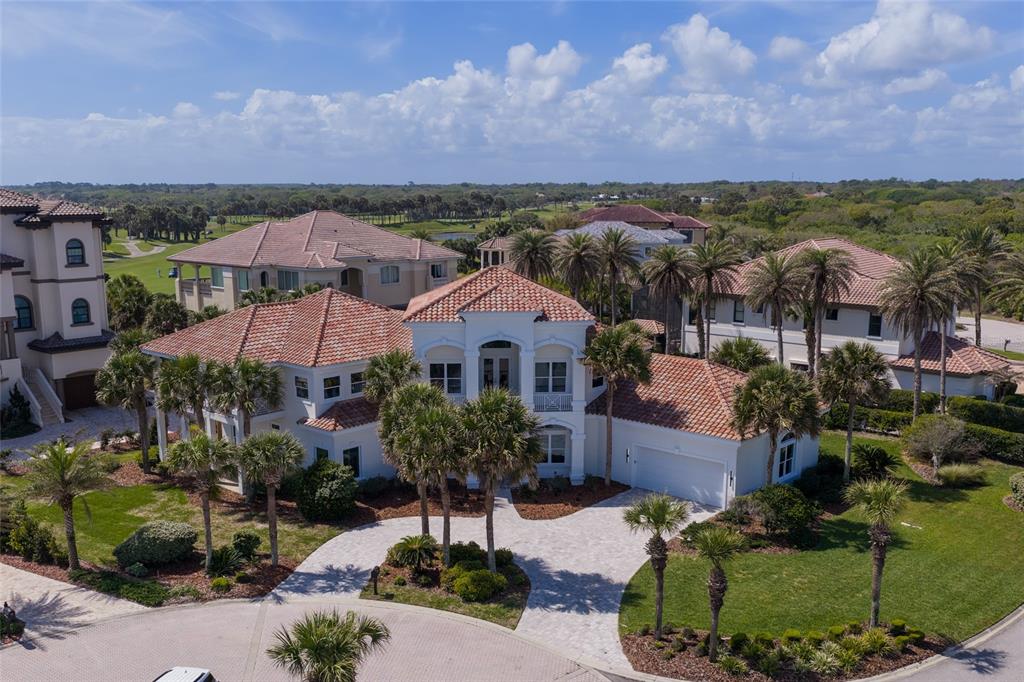 An aerial view shows a two-story Mediterranean-style house with a tile roof and palm trees — 6 RIVIERA PLACE, PALM COAST, FL