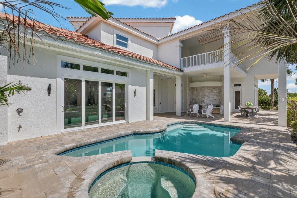 A backyard features a swimming pool, a circular spa, and a covered patio with outdoor seating — 6 RIVIERA PLACE, PALM COAST, FL