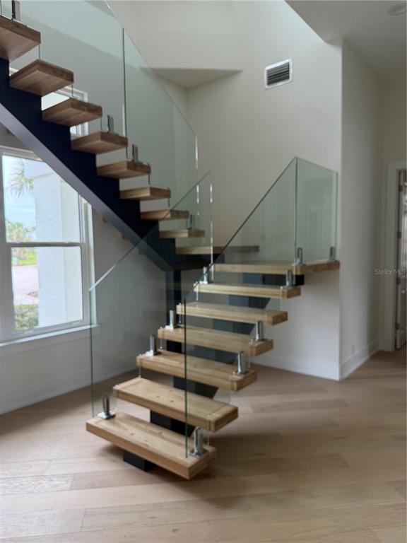 A modern entryway features light wood floors, white walls, and a floating wooden staircase — 6 RIVIERA PLACE, PALM COAST, FL