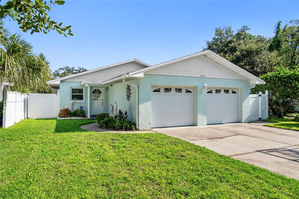 A light blue single-story house features a two-car garage, a white front door, and landscaping — 1621 CHESTNUT AVENUE, WINTER PARK, FL