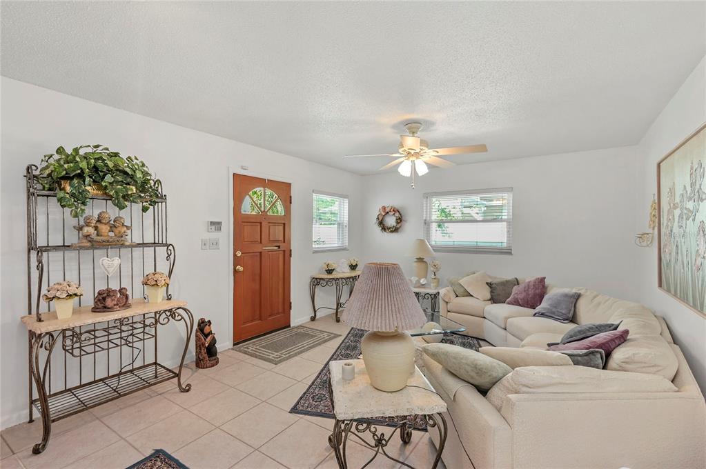 A living room with tile floors, a beige sectional sofa, and a wooden front door — 1621 CHESTNUT AVENUE, WINTER PARK, FL