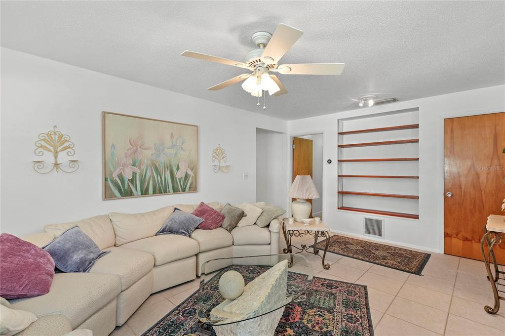 A living room features a beige sectional sofa, a glass coffee table, and built-in wall shelving — 1621 CHESTNUT AVENUE, WINTER PARK, FL