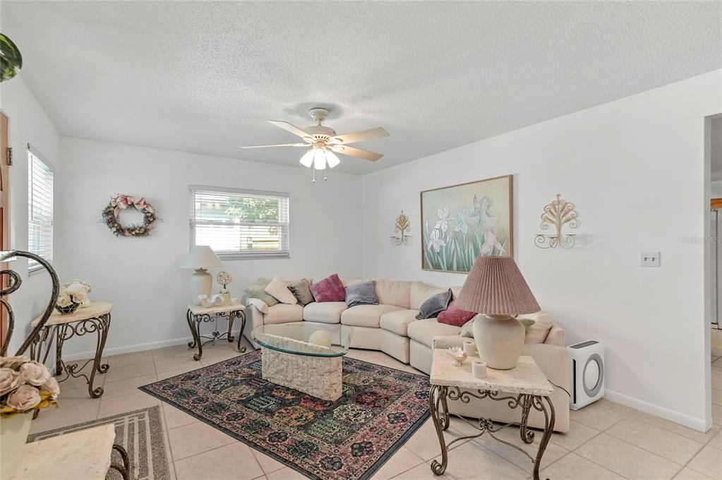 A living room features a beige sectional sofa, a glass coffee table, and a patterned rug — 1621 CHESTNUT AVENUE, WINTER PARK, FL