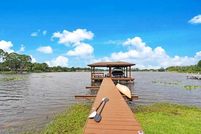 A wooden dock extends into a lake toward a covered boat slip with a kayak — 4512 BRIDGEWATER DRIVE, ORLANDO, FL