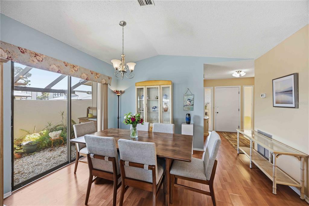 A dining room with a wooden table, six chairs, a china cabinet, and sliding glass doors — 38 PEBBLE ROCK DRIVE, VENICE, FL
