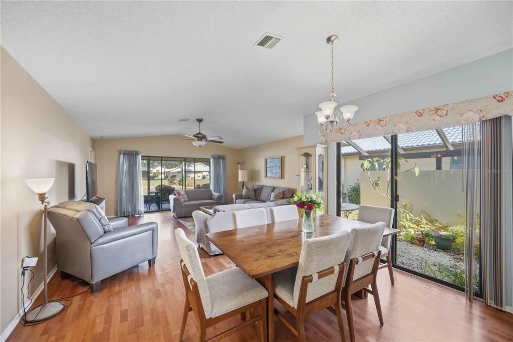 A dining area and living room with hardwood floors, a chandelier, and sliding glass doors — 38 PEBBLE ROCK DRIVE, VENICE, FL