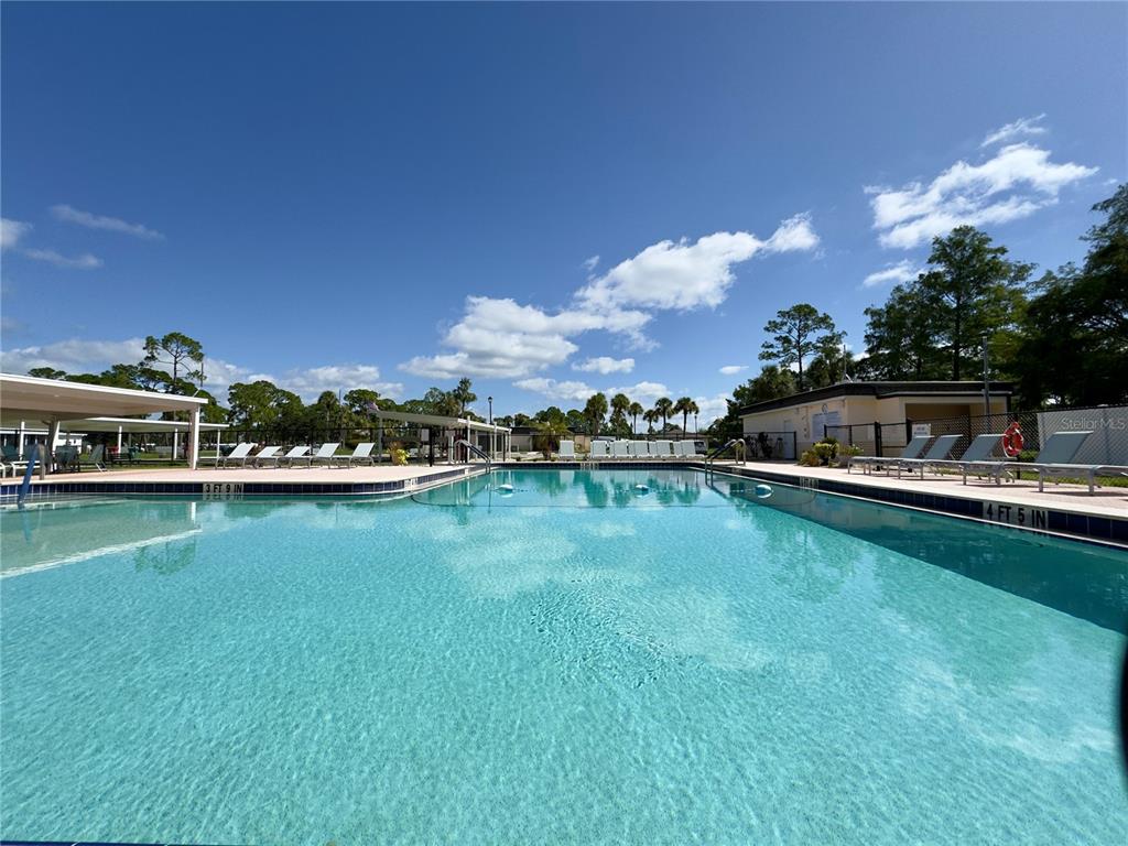 A rectangular outdoor swimming pool is surrounded by lounge chairs and a covered patio area — 6965 APOPO COURT, NORTH PORT, FL