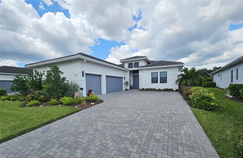 A single-story white house with a paved driveway, two-car garage, and a tiled roof — 4952 SURFSIDE CIRCLE, BRADENTON, FL