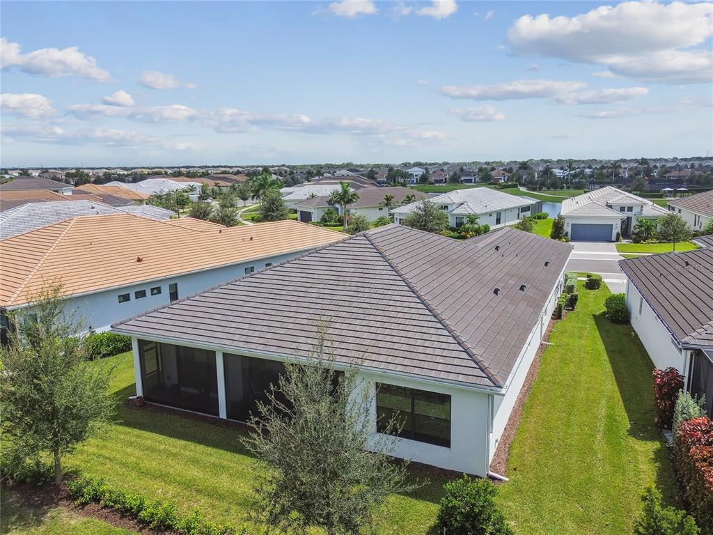 An aerial view shows the back of a house with a screened-in porch and yard — 4952 SURFSIDE CIRCLE, BRADENTON, FL