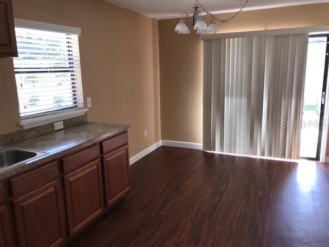 A kitchen with wood cabinets and laminate countertops opens into a dining area with wood flooring — 437 E OAKWOOD AVENUE, ORANGE CITY, FL