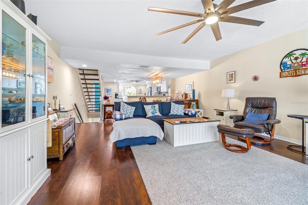 A living room features a blue sectional sofa, a leather recliner, and dark wood flooring — 751 PINELLAS BAYWAY S UNIT 208, TIERRA VERDE, FL